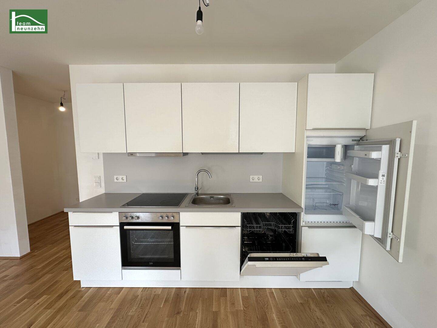 Moderne Einbauküche mit weißen Schränken, Induktionskochfeld und integrierten Geräten.