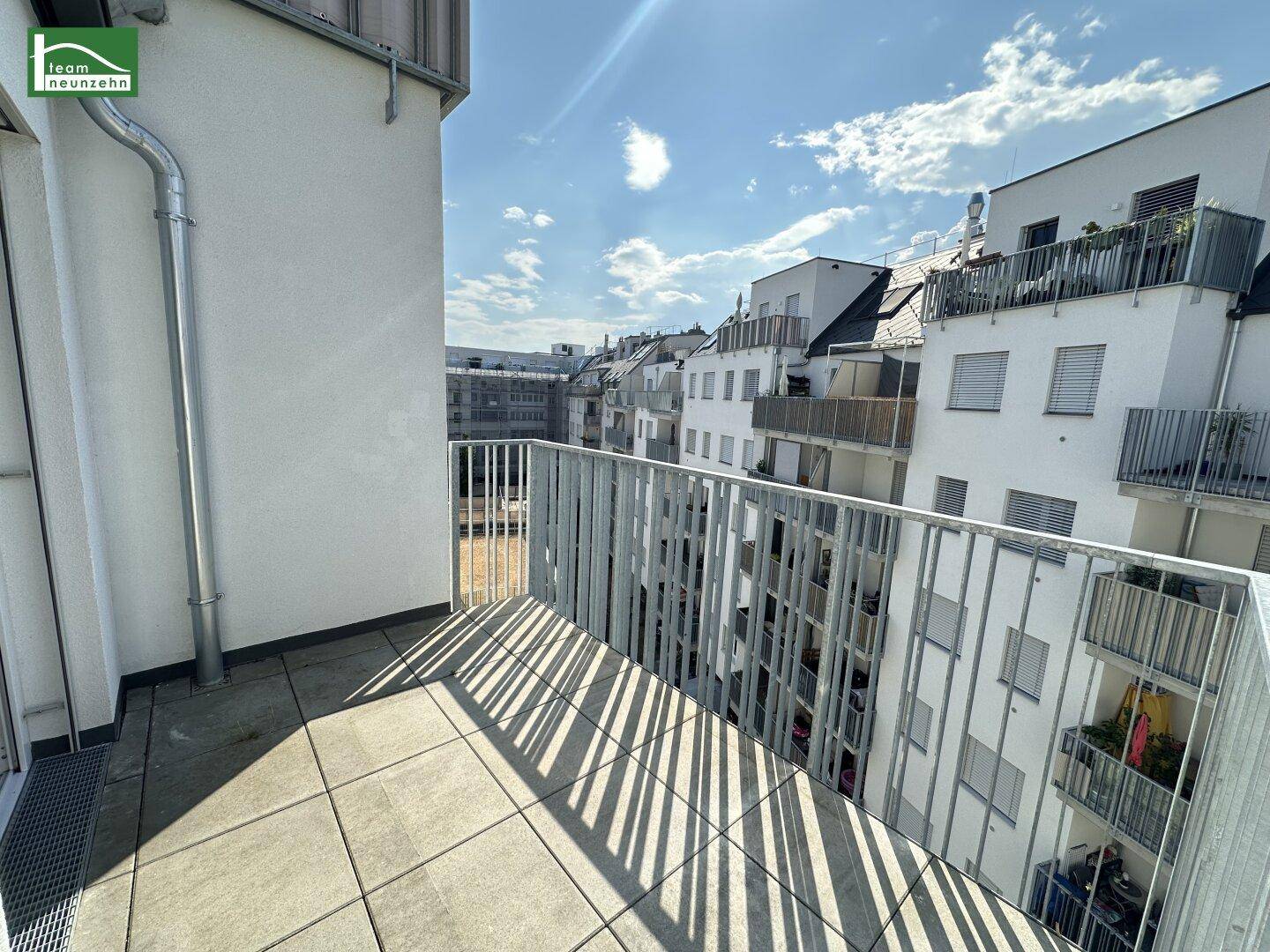 Sonniger Balkon mit Fliesenboden und Blick auf die umliegenden Wohngebäude.
