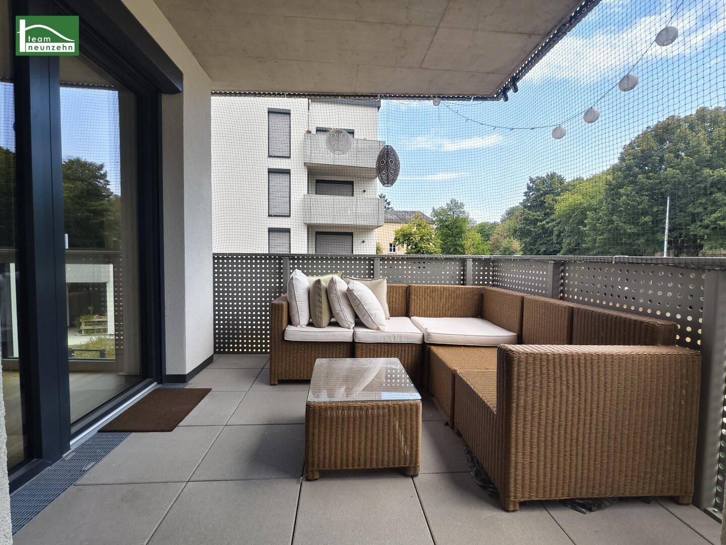 Gemütlicher Balkon mit Rattan-Sitzgruppe und Blick auf die umliegenden Gebäude.