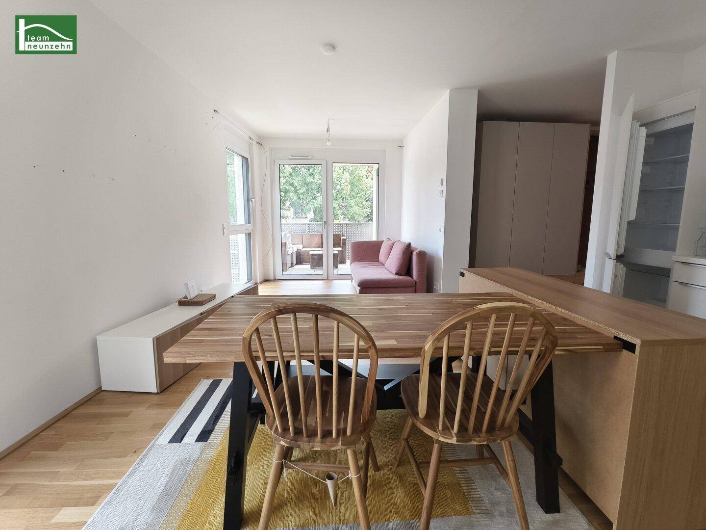 Heller Wohn- und Essbereich mit Holzboden und Zugang zu einem Balkon.