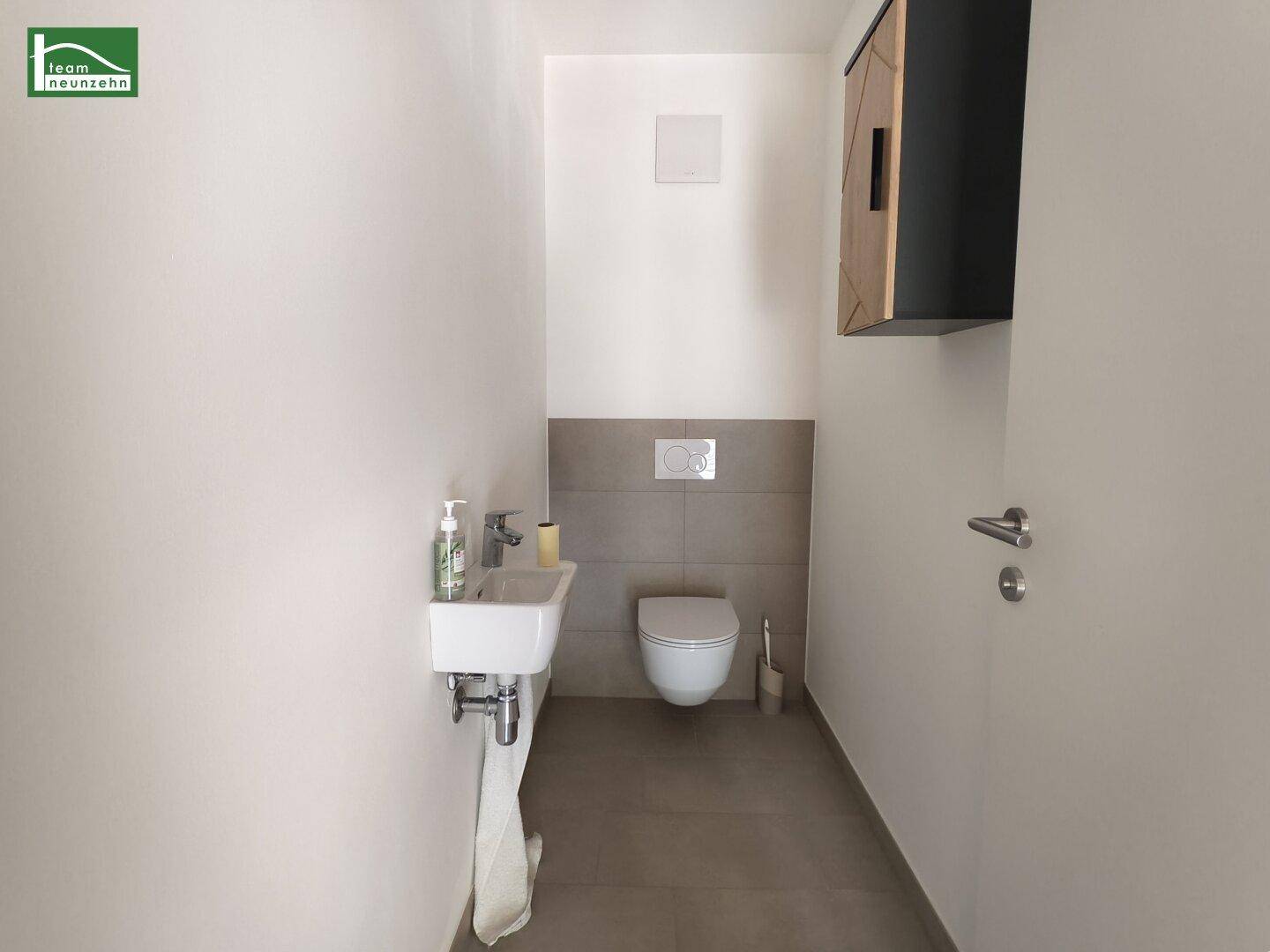 Separates Gäste-WC mit modernem Wand-WC und kleinem Handwaschbecken.