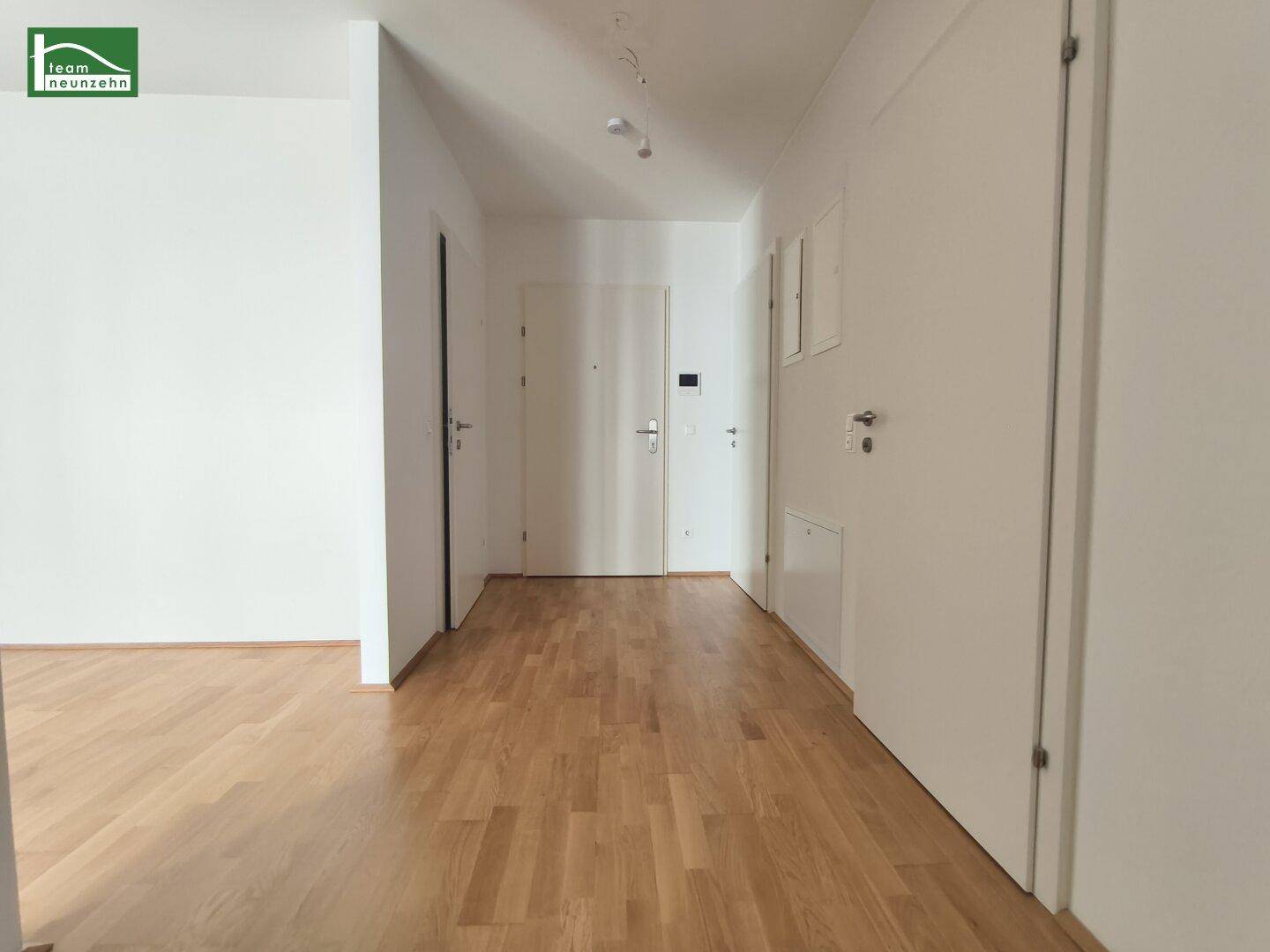 Heller Eingangsbereich mit Parkettboden und mehreren Türen, führt zu den verschiedenen Räumen.