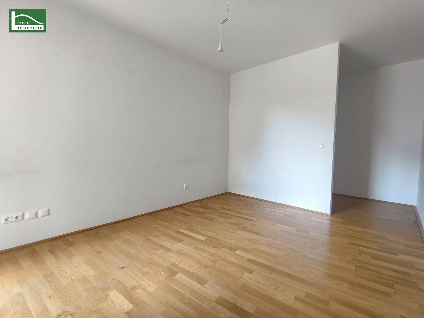Leerer Raum mit hellem Parkettboden und weißen Wänden, bietet flexible Gestaltungsmöglichkeiten.