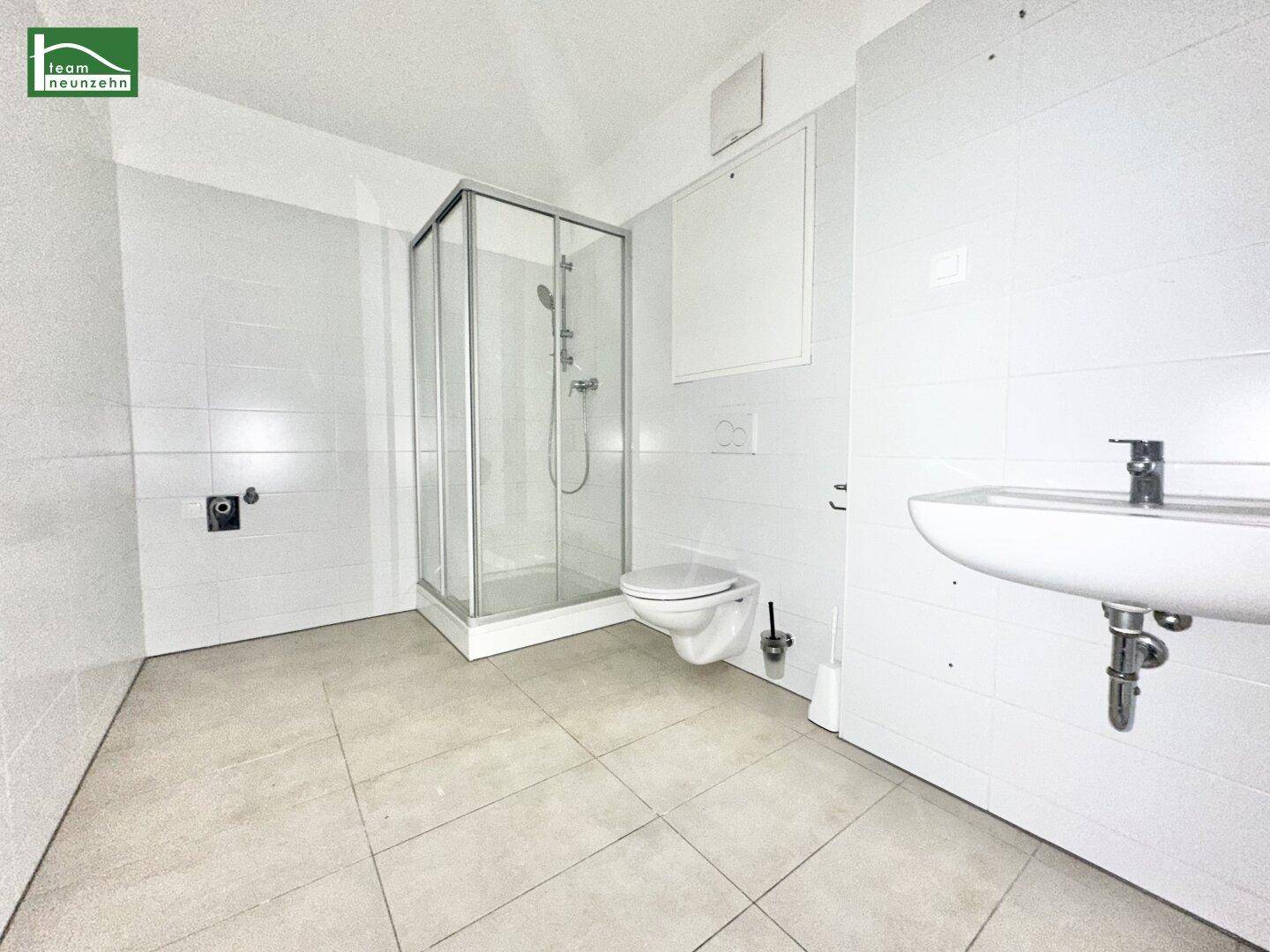Modernes Badezimmer mit weißen Fliesen, Duschkabine, wandhängendem WC und Einzelwaschbecken.