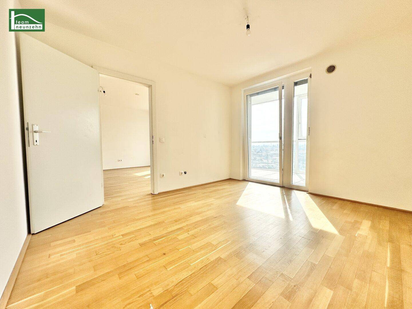 Helles Zimmer mit Parkettboden und großen Schiebetüren, die viel Tageslicht hereinlassen.