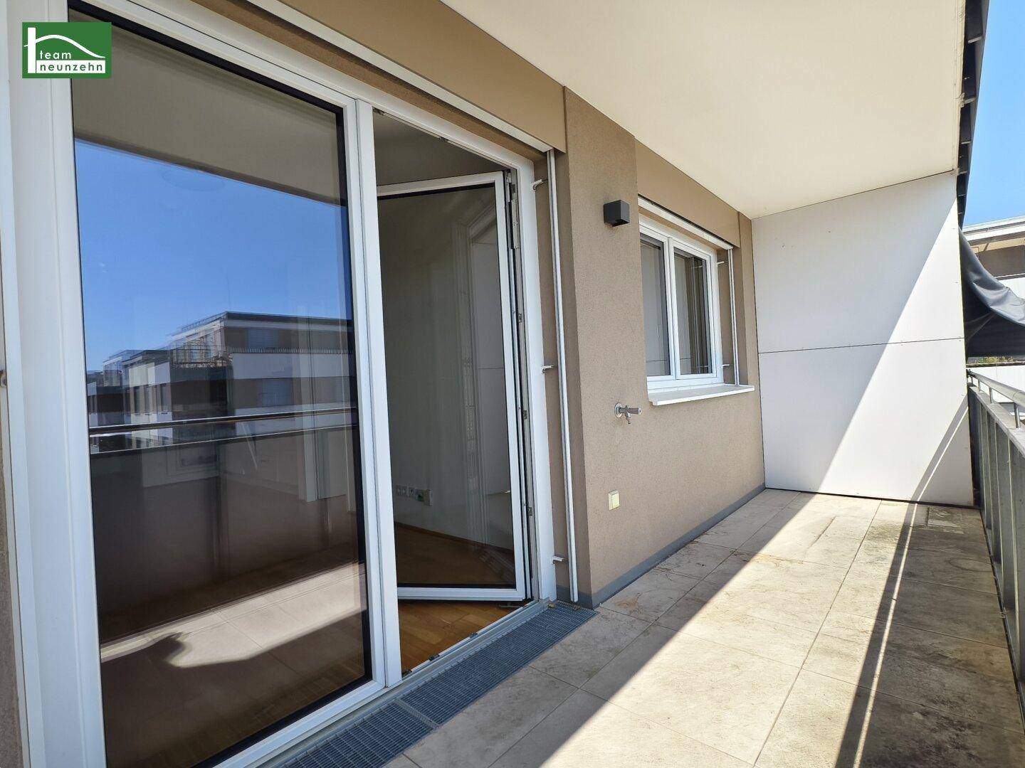 Balkon mit Fliesenboden und Zugang zum Innenbereich durch eine große Glastür.