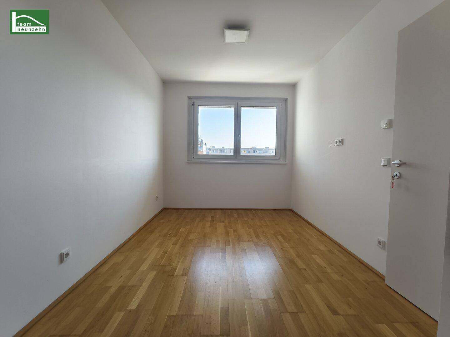 Helles Schlafzimmer mit Eichenparkettboden und einem großen Fenster.