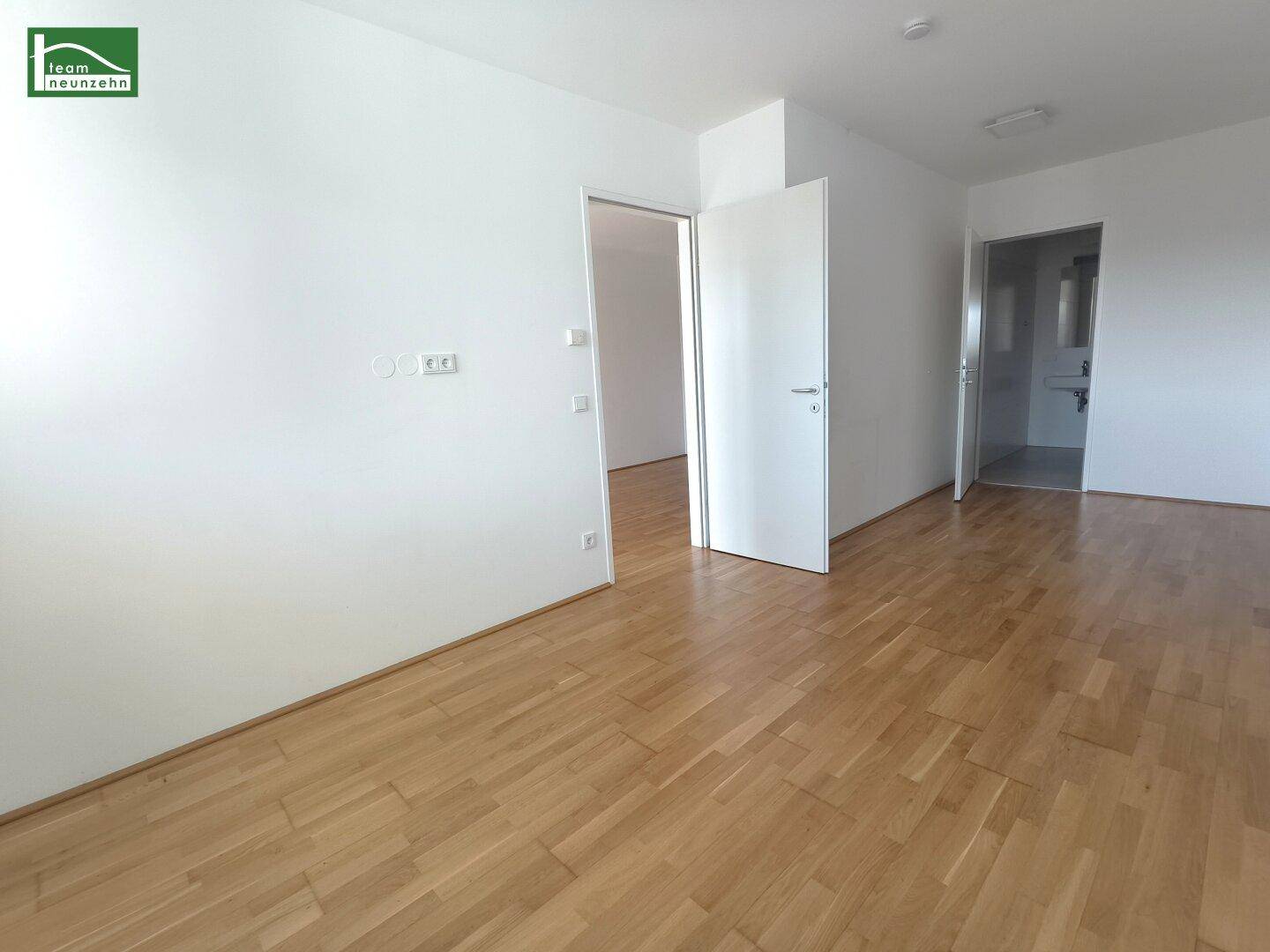 Heller Innenraum mit Eichenparkettboden und mehreren Türen zu angrenzenden Räumen.