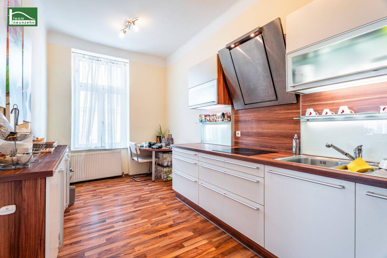 Funktionale Küche mit Holzboden, modernen Schränken und einem Fenster.
