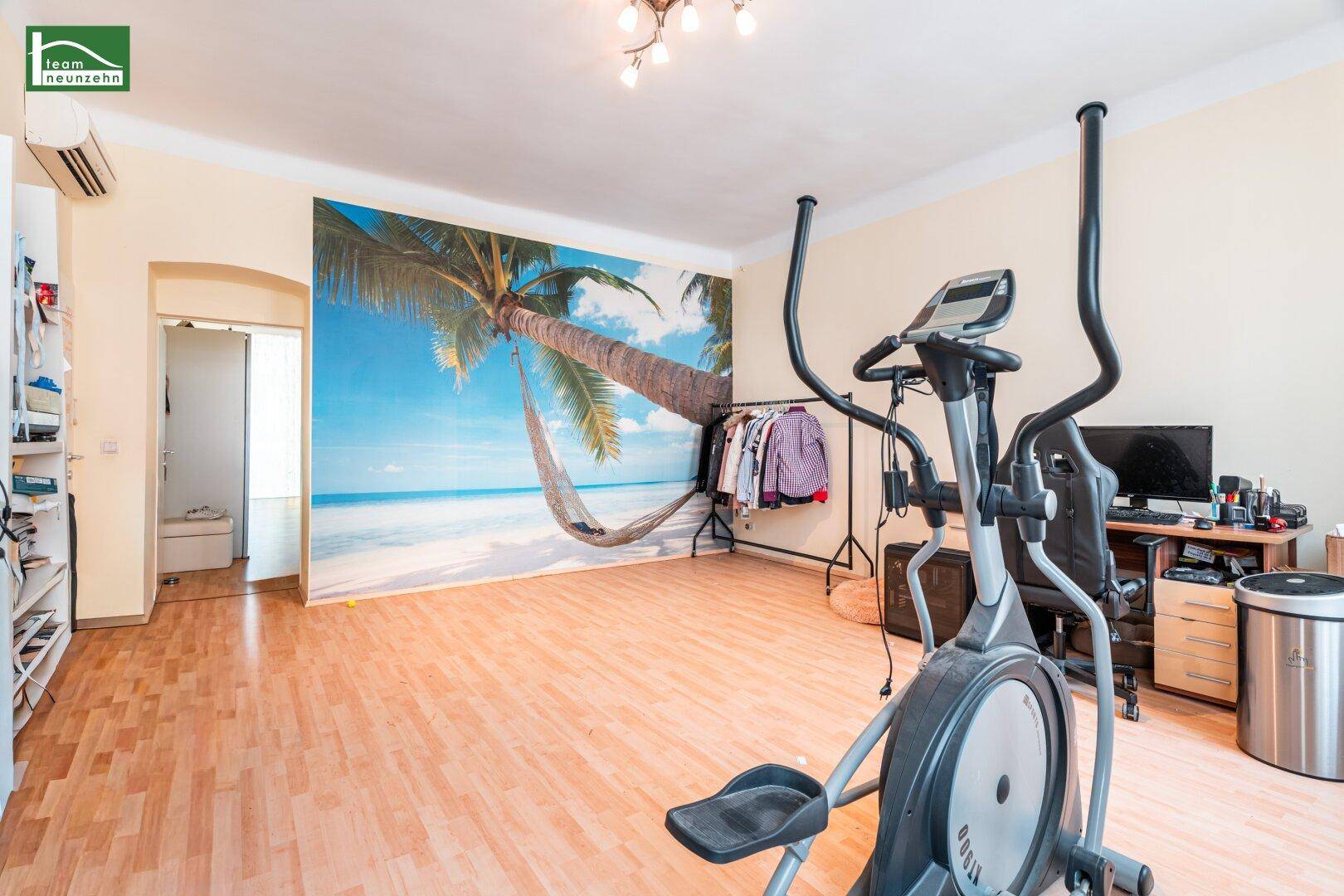 Vielseitiger Raum mit Fitnessgerät, Schreibtisch und einer dekorativen Wandtapete.