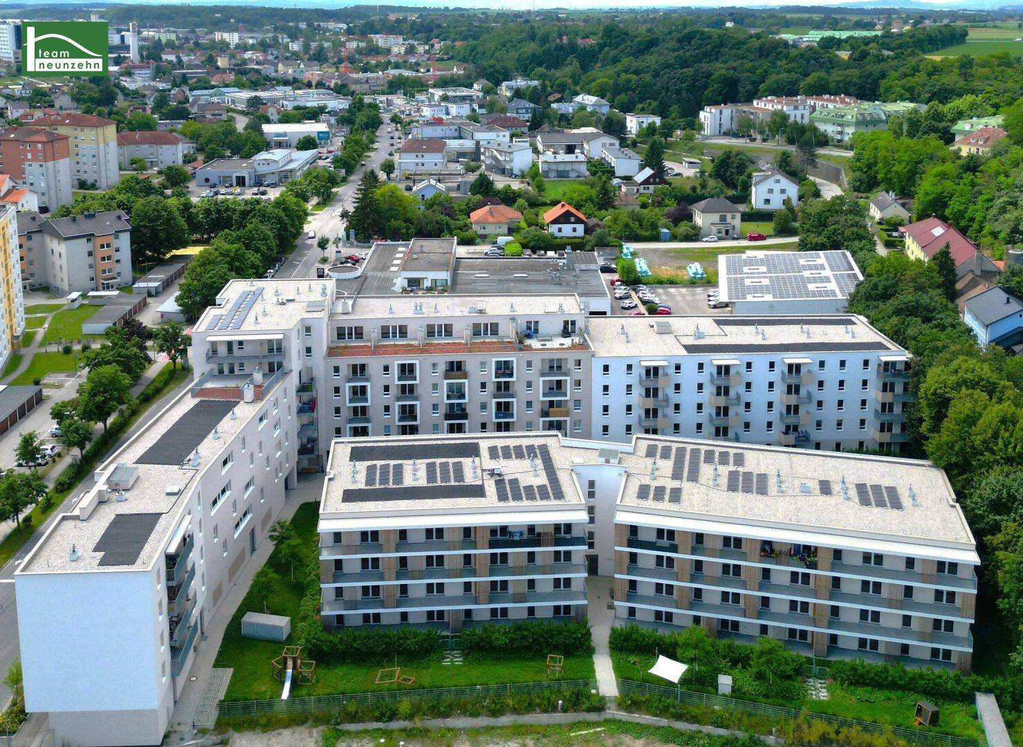 Luftaufnahme eines modernen Wohnkomplexes mit mehreren Gebäuden und Grünflächen.