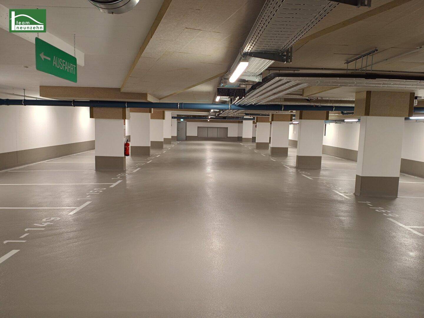 Geräumige Tiefgarage mit vielen Stellplätzen und klarer Beschilderung für die Ausfahrt.