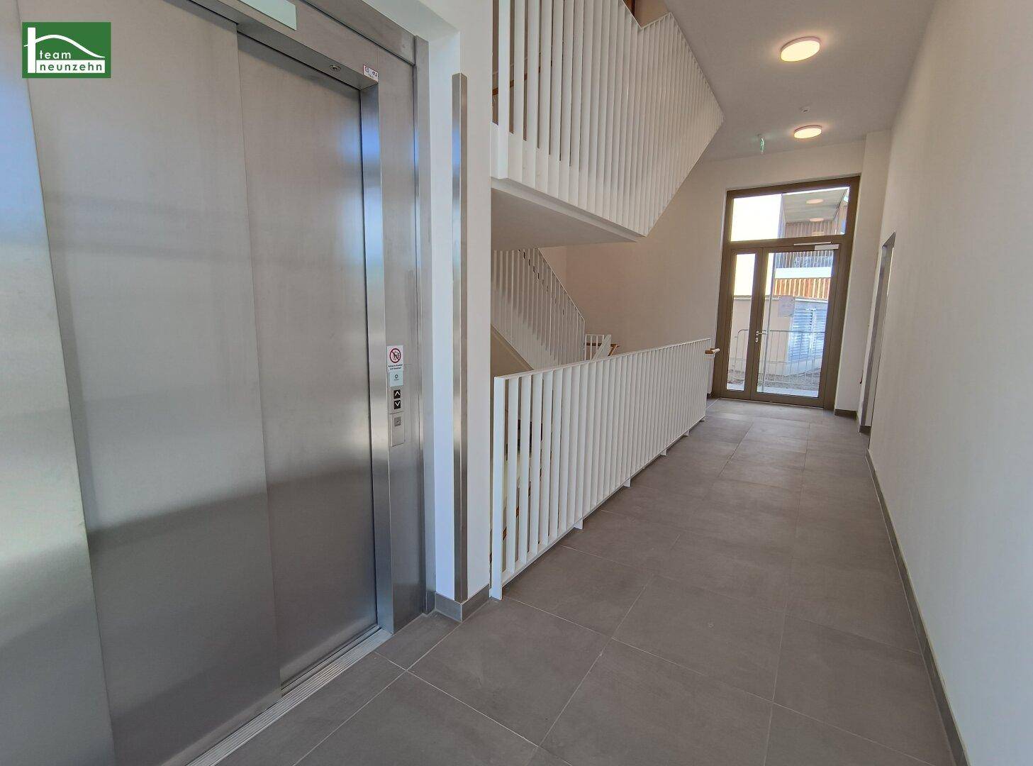 Heller Flur im Treppenhaus mit modernem Aufzug und Zugang zu den Wohnungen.