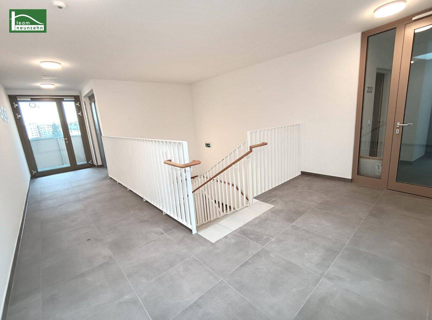 Geräumiges Treppenhaus mit hellem Fliesenboden und Zugang zu den oberen Etagen.