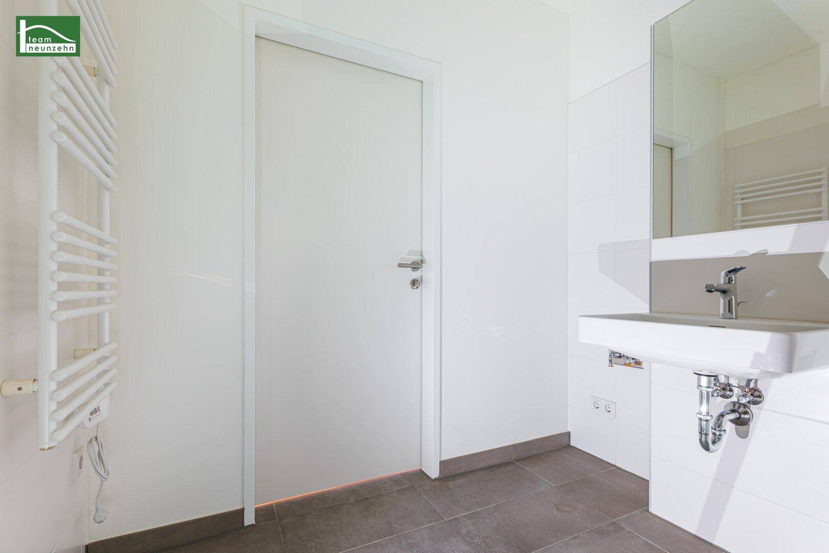 Modernes Badezimmer mit Waschbecken, Spiegel und beheiztem Handtuchhalter.