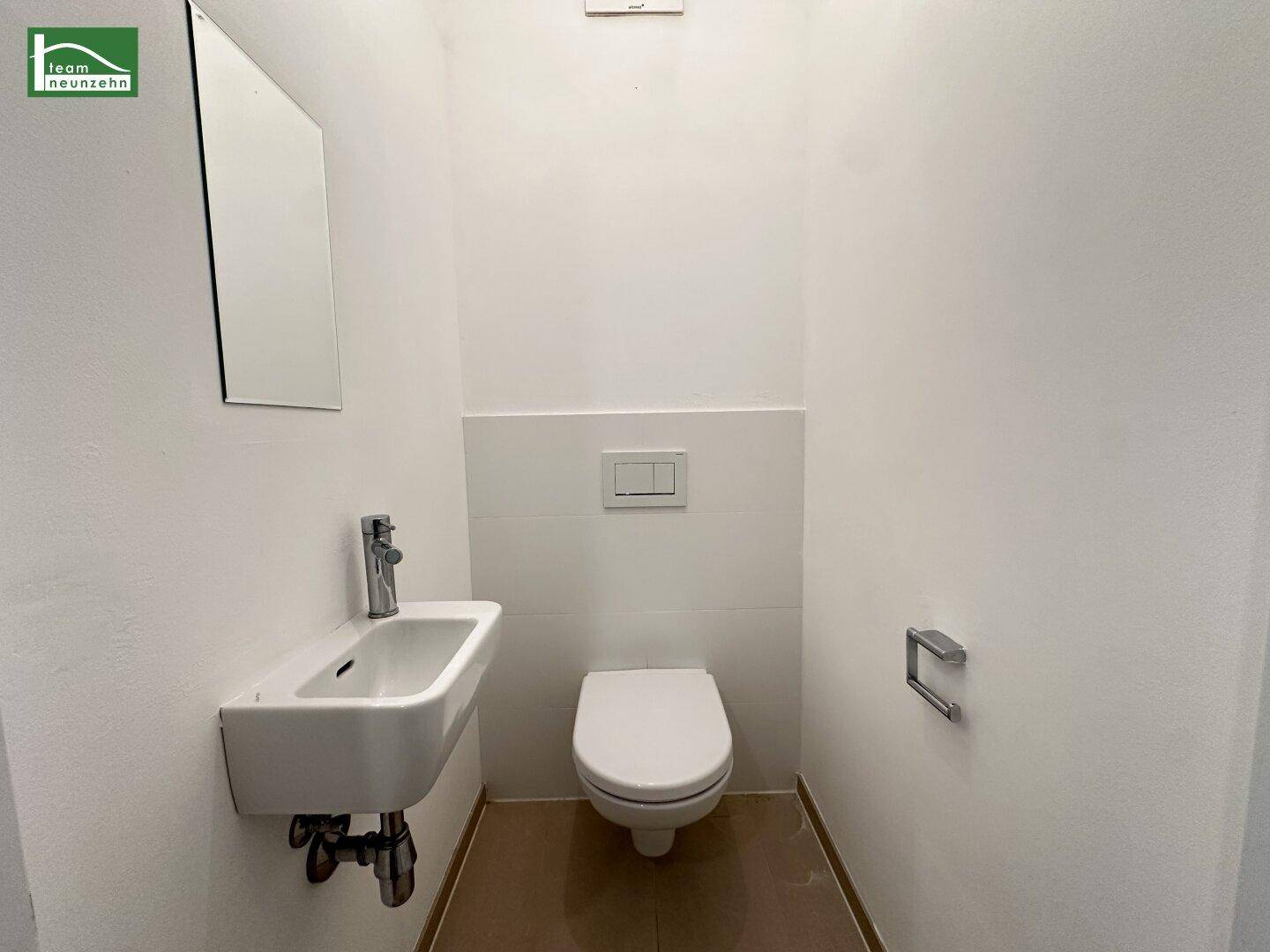 Separates Gäste-WC mit wandhängendem WC und kleinem Waschbecken.