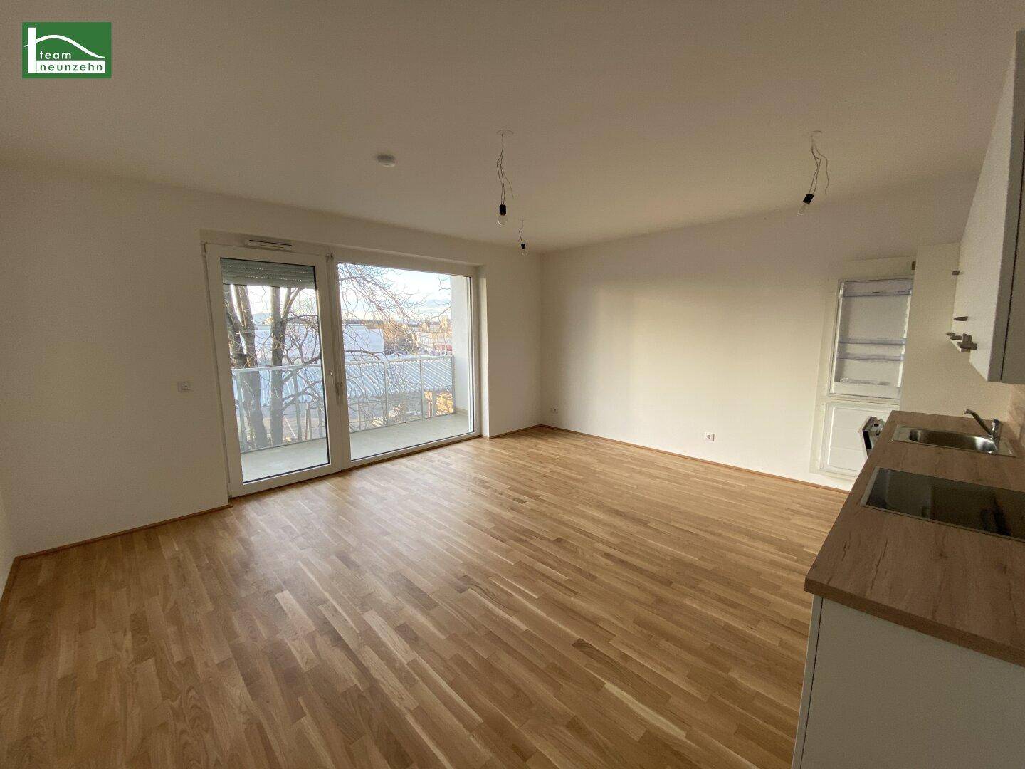 Lichtdurchfluteter Wohnbereich mit großem Fenster und Zugang zum Balkon, ideal für entspannte Stunden.