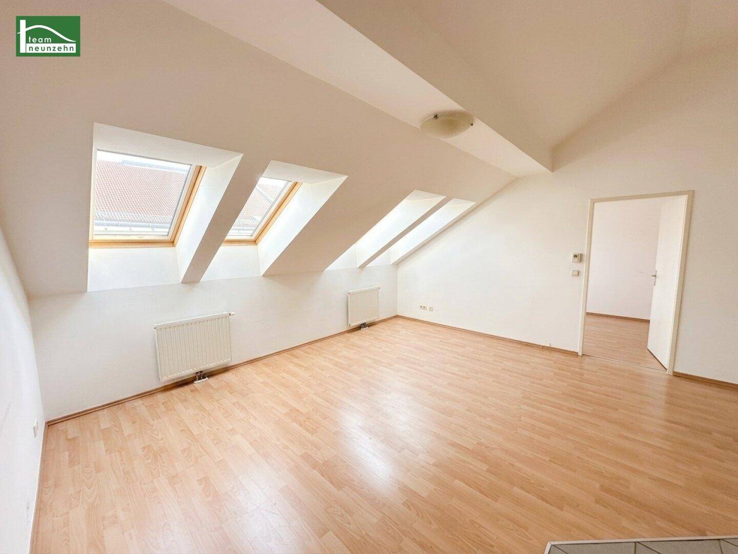 Geräumiges Zimmer im Dachgeschoss mit Holzboden und mehreren schrägen Dachfenstern.
