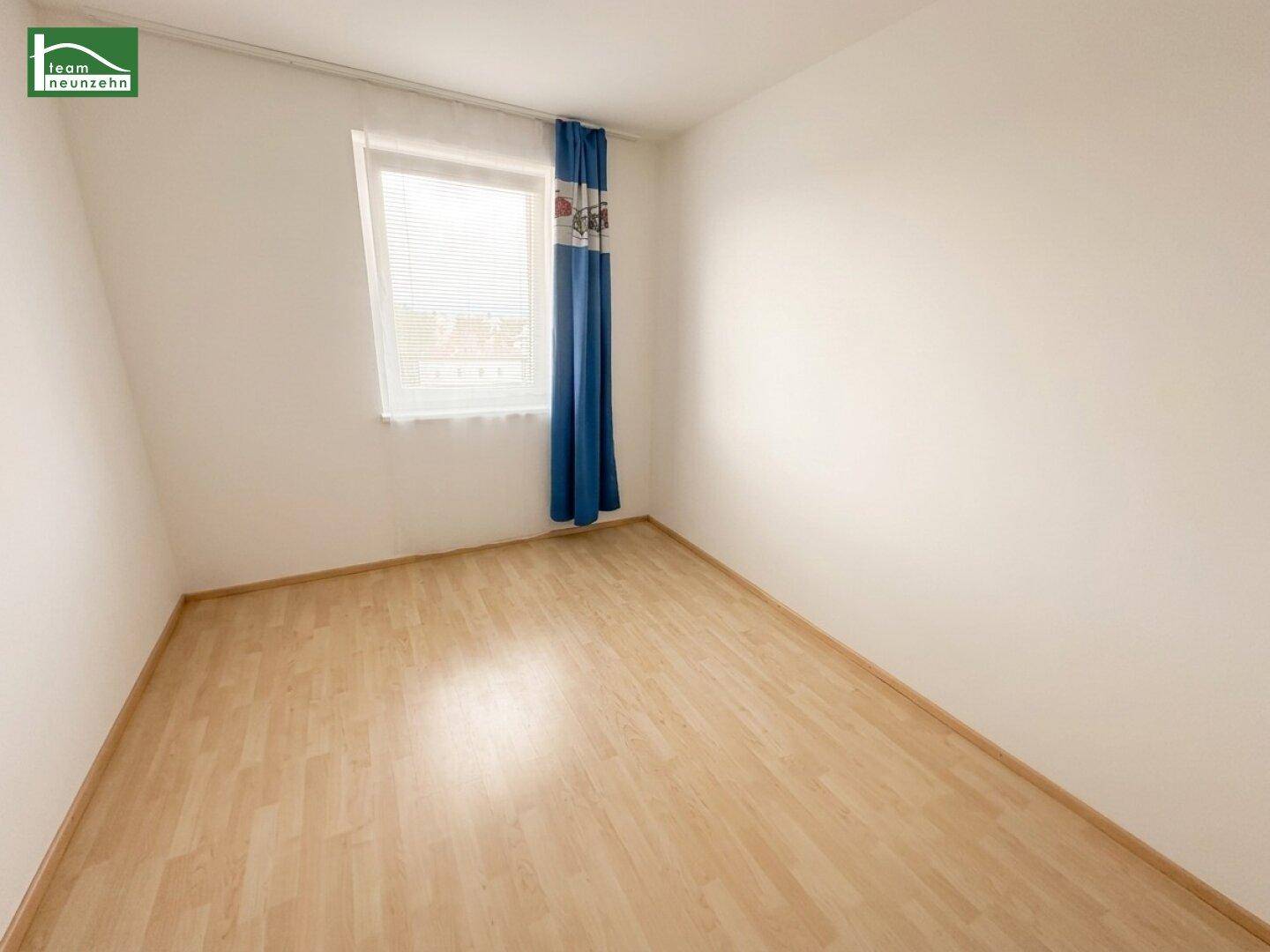 Helles Zimmer mit Laminatboden und einem Fenster, das viel Tageslicht hereinlässt.