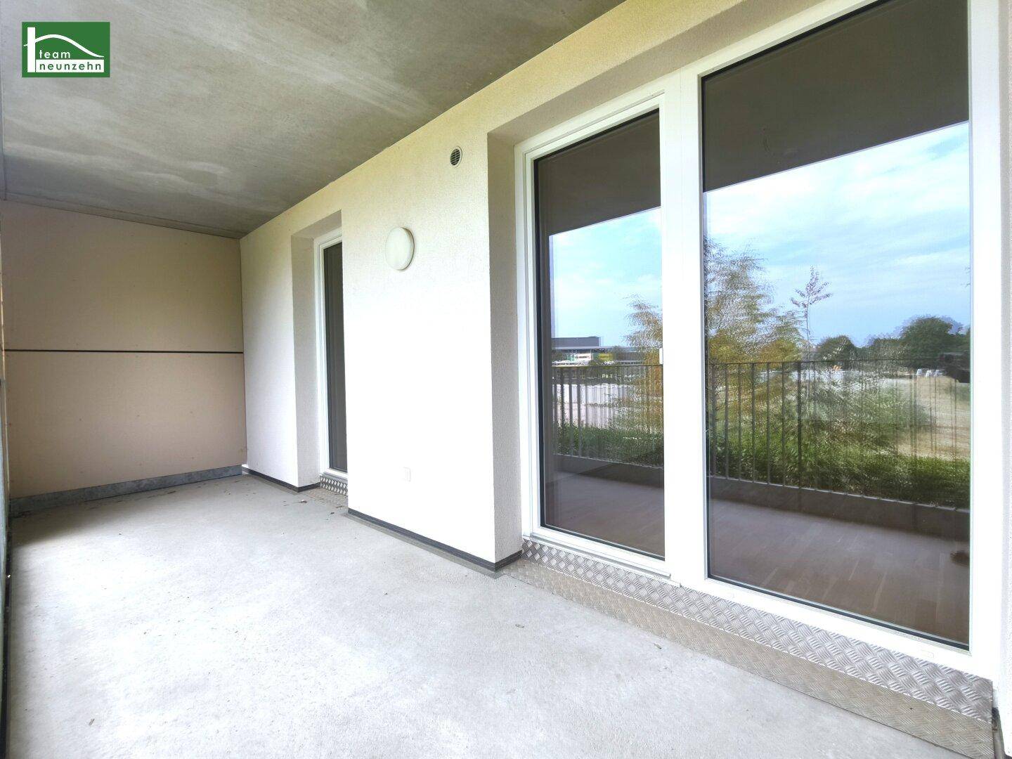 Überdachter Balkon mit großen Fenstern und Türen, die viel Tageslicht in den angrenzenden Raum lassen.