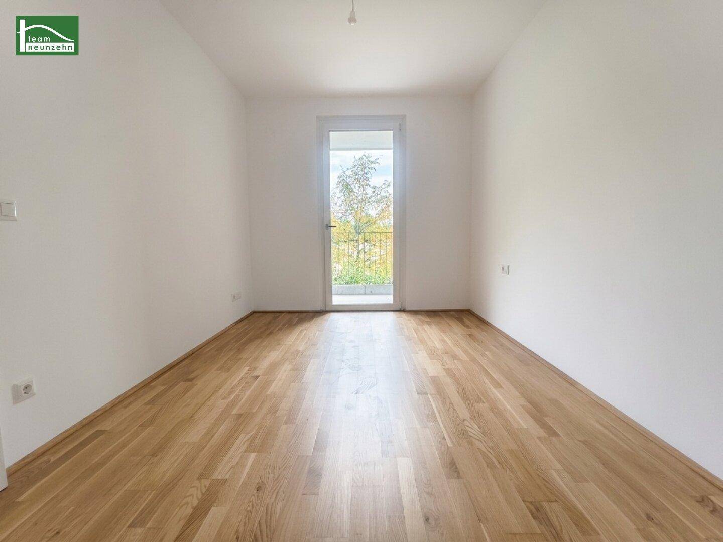 Helles Schlafzimmer mit Parkettboden und Zugang zu einem kleinen Balkon, ideal für frische Luft.