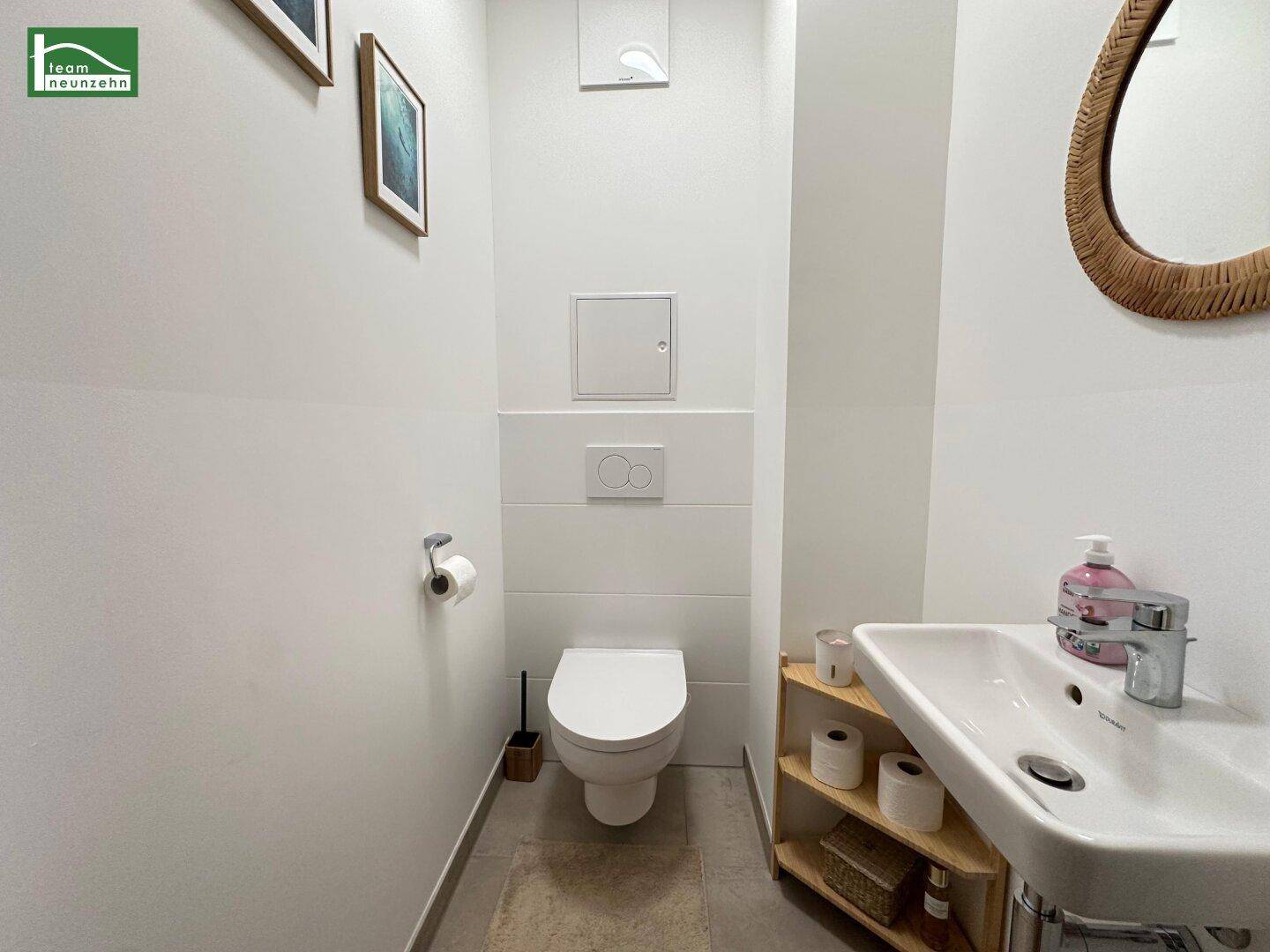 Kleines Gäste-WC mit wandhängender Toilette und Waschbecken, in hellen Farben gehalten.
