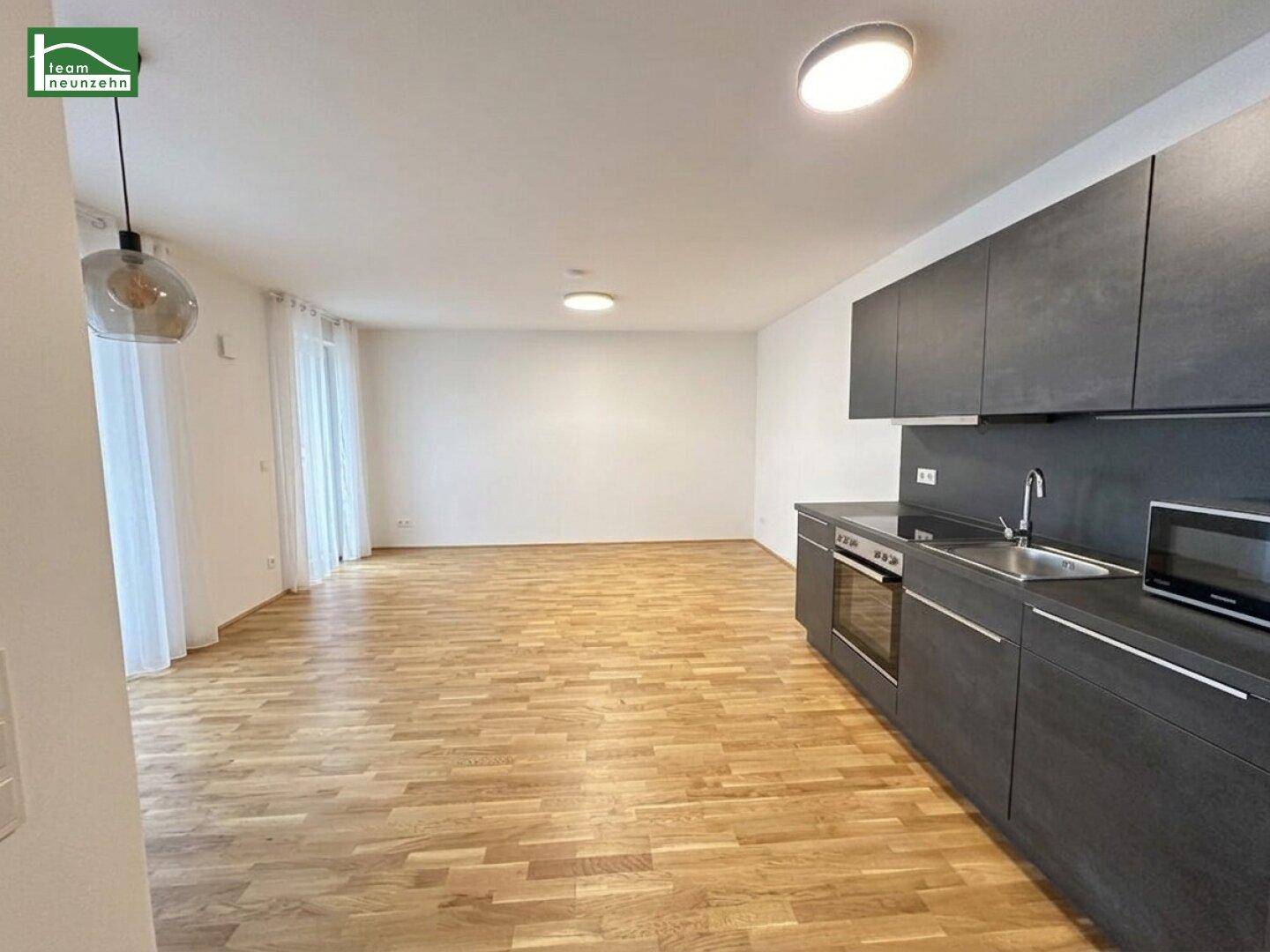 Offener Wohnbereich mit integrierter Küchenzeile und Parkettboden, ideal für modernes Wohnen.