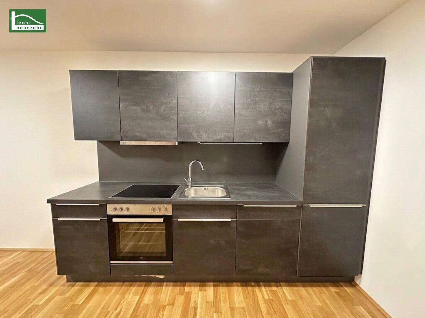 Moderne Einbauküche in Dunkelgrau mit integriertem Backofen und Induktionskochfeld.