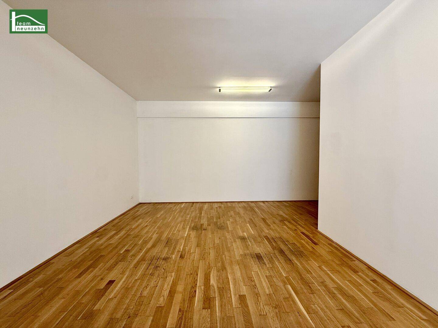 Schlichter, leerer Raum mit Holzboden und weiß gestrichenen Wänden, bereit zur individuellen Gestaltung.