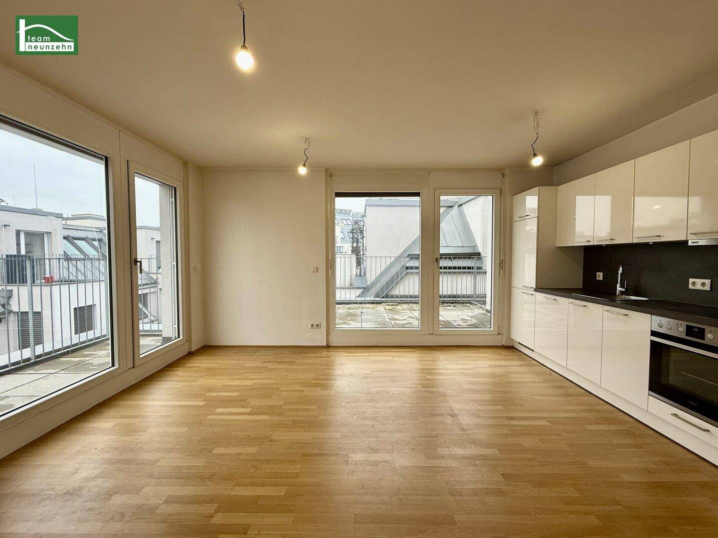 Geräumiger, leerer Wohn- und Essbereich mit Parkettboden und großen Fenstern zur Terrasse.