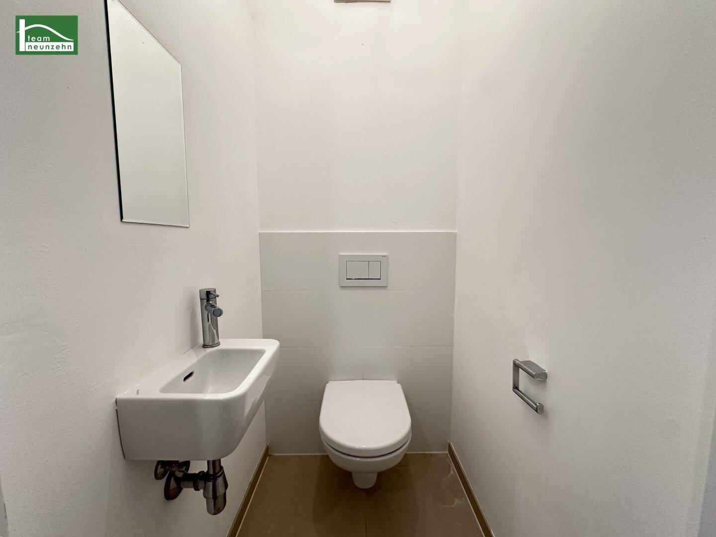 Modernes Gäste-WC mit wandhängendem WC und kleinem Waschbecken in schlichtem Design.
