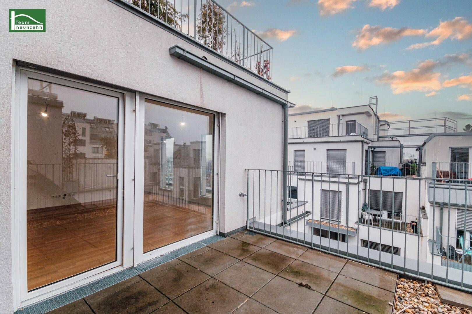 Geräumige Terrasse mit Fliesenboden und Blick auf die umliegenden modernen Gebäude.