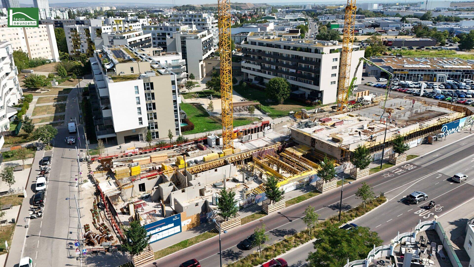 Luftaufnahme einer Baustelle mit Kränen und umliegenden modernen Wohngebäuden in städtischer Umgebung.