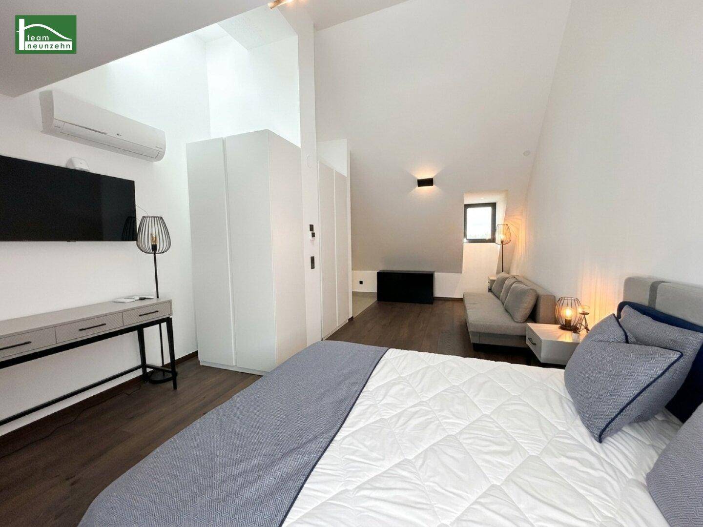 Modernes Schlafzimmer im Dachgeschoss mit Holzboden, Klimaanlage und Fernseher.