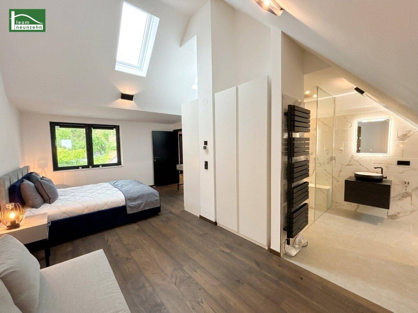 Schlafzimmer mit Holzboden und offenem Zugang zu einem modernen Badezimmer mit Dusche.