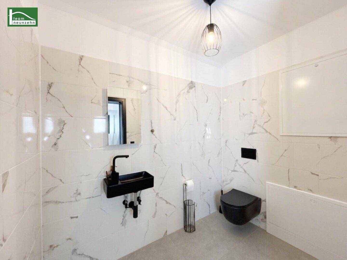 Modernes Gäste-WC mit schwarzen Armaturen und Marmoroptik-Fliesen.