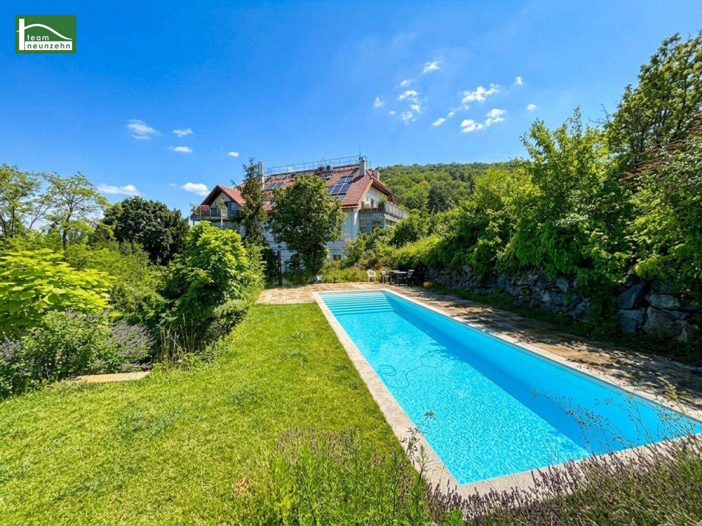 Großer Garten mit Swimmingpool und Blick auf das Hauptgebäude und die umliegende Natur.