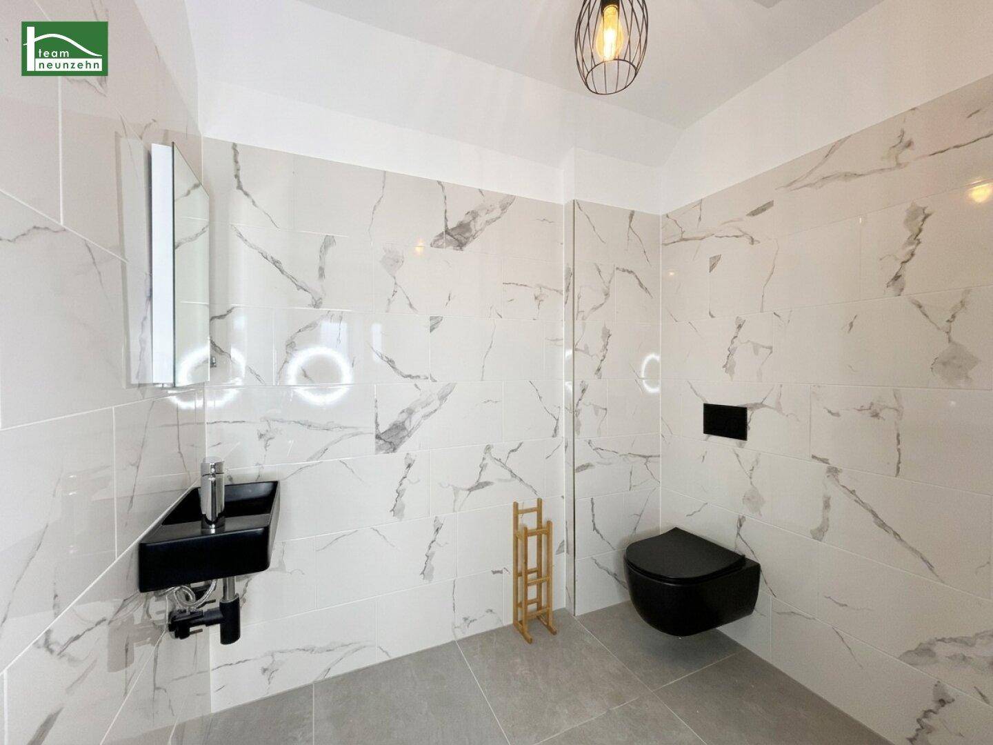 Elegantes Gäste-WC mit modernen Marmorfliesen und wandhängender Toilette.