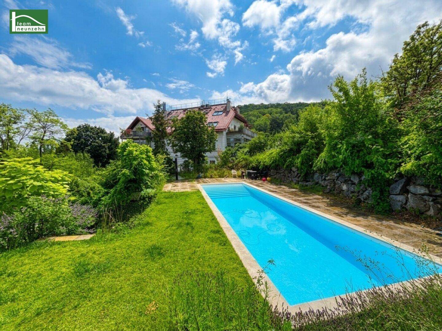 Großer Außenpool in einem gepflegten Garten mit Blick auf das Haus und die grüne Umgebung.