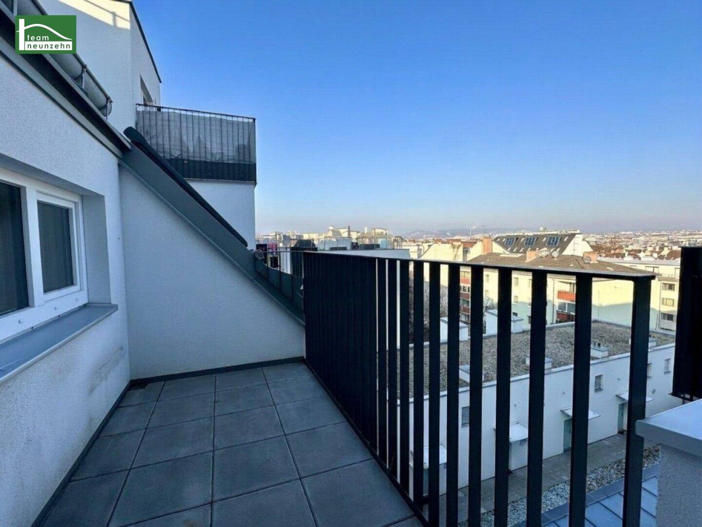 Geräumige Terrasse mit Fliesenboden und weitem Blick über die Dächer der Stadt.
