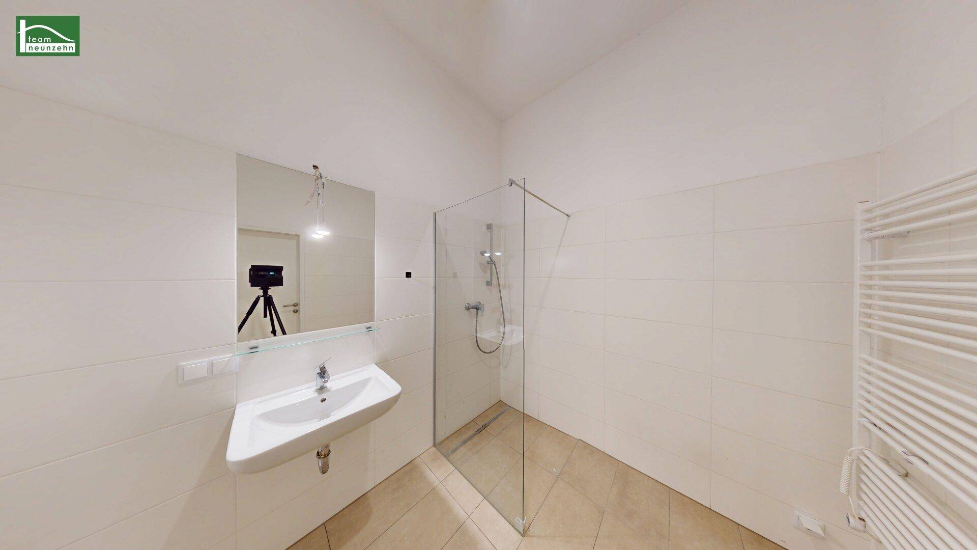 Modernes Badezimmer mit begehbarer Dusche, Wandwaschbecken und praktischem Handtuchheizkörper.