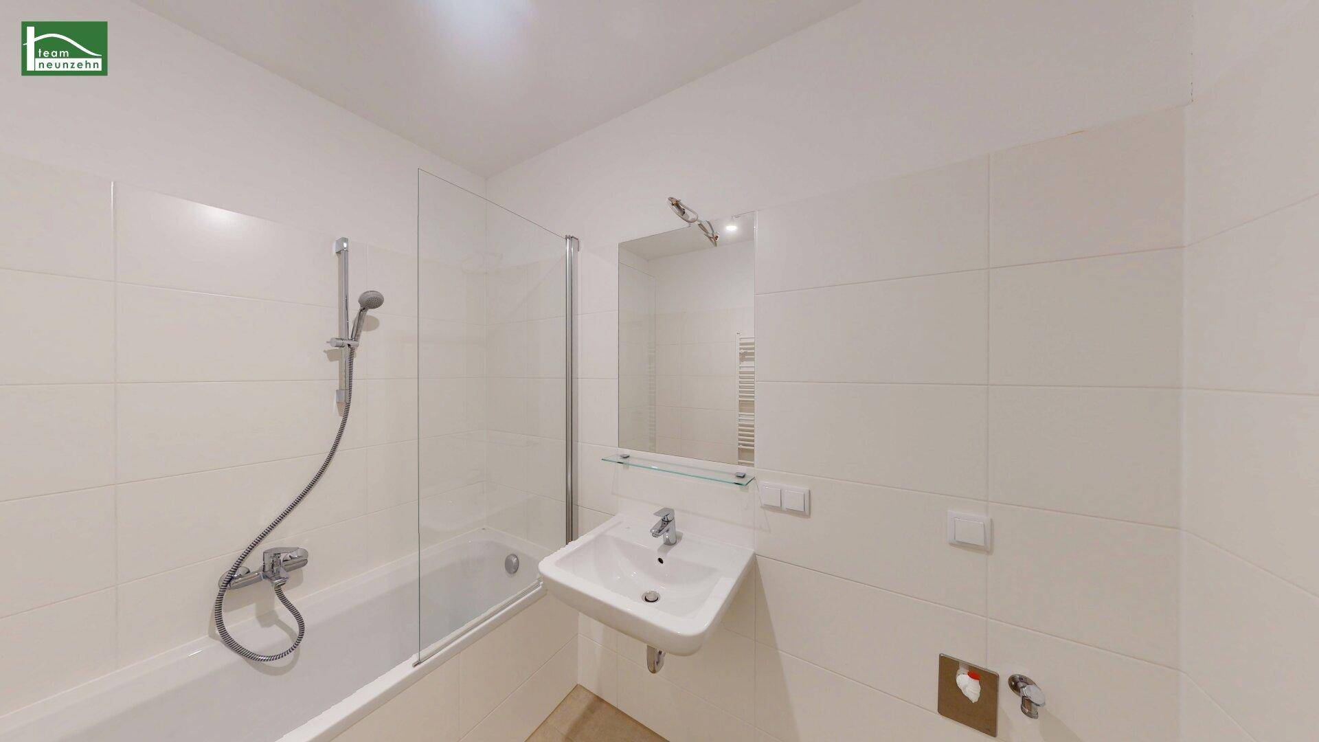 Modernes Badezimmer mit Badewanne, Duschabtrennung, Waschbecken und weißen Fliesen.