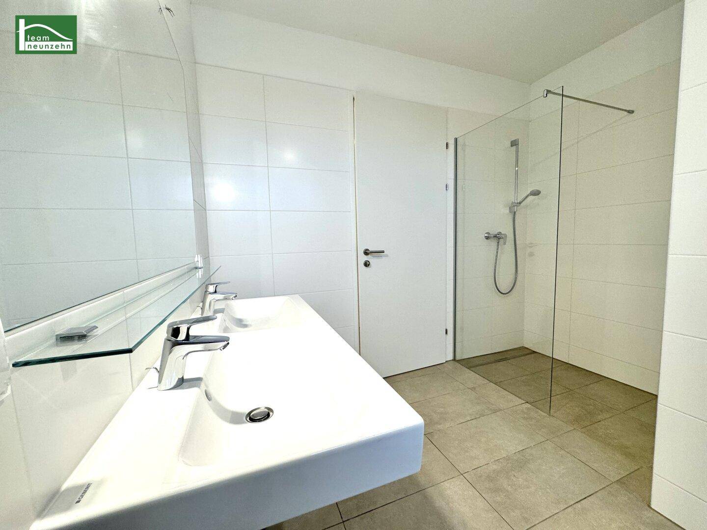 Modernes Badezimmer mit Doppelwaschbecken, großer Spiegelfläche und ebenerdiger Dusche.