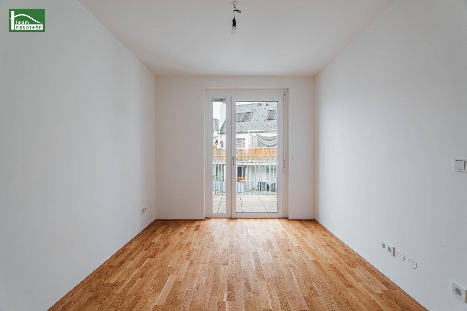 Helles Zimmer mit Parkettboden, weißen Wänden und direktem Zugang zum Balkon.