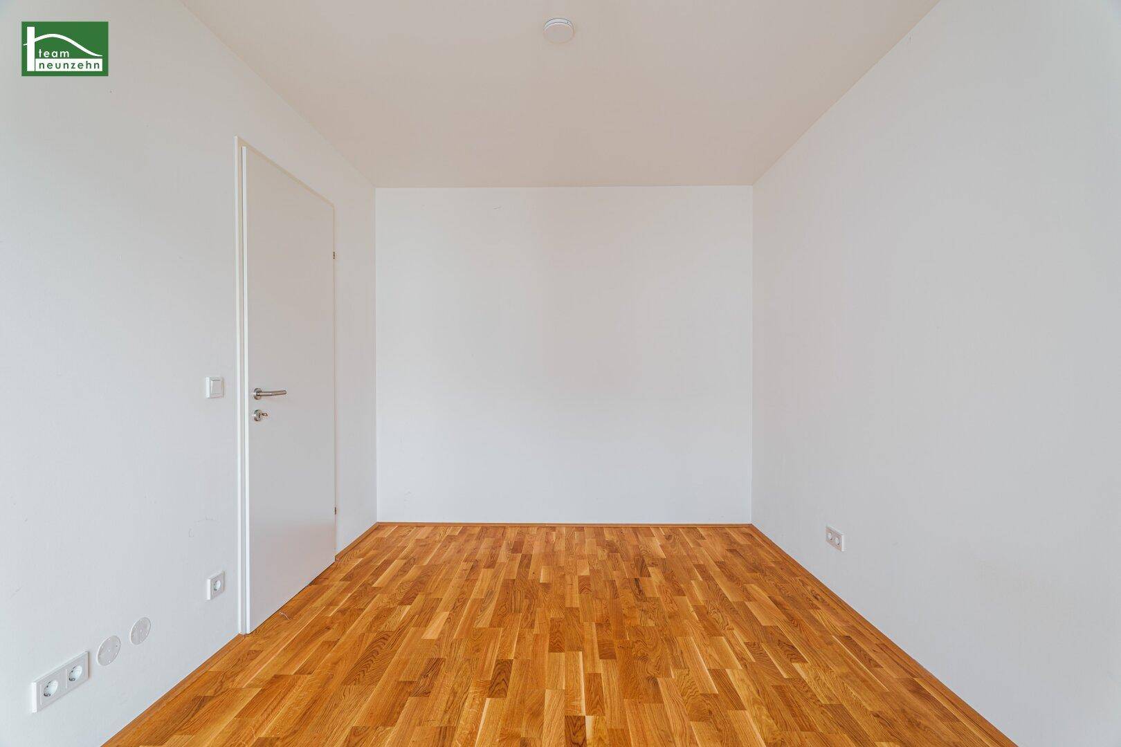 Leeres Zimmer mit Parkettboden und weißen Wänden, bereit zur individuellen Gestaltung.
