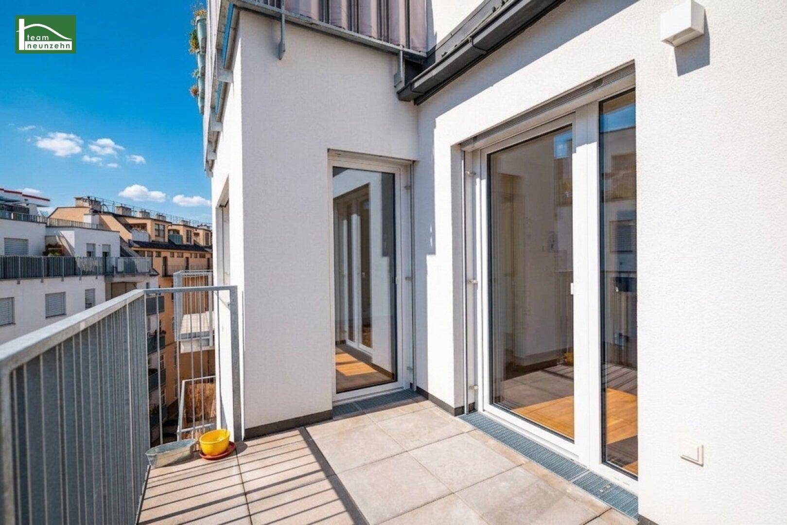 Sonniger Balkon mit Fliesenboden und Zugangstüren zu den Innenräumen des Gebäudes.