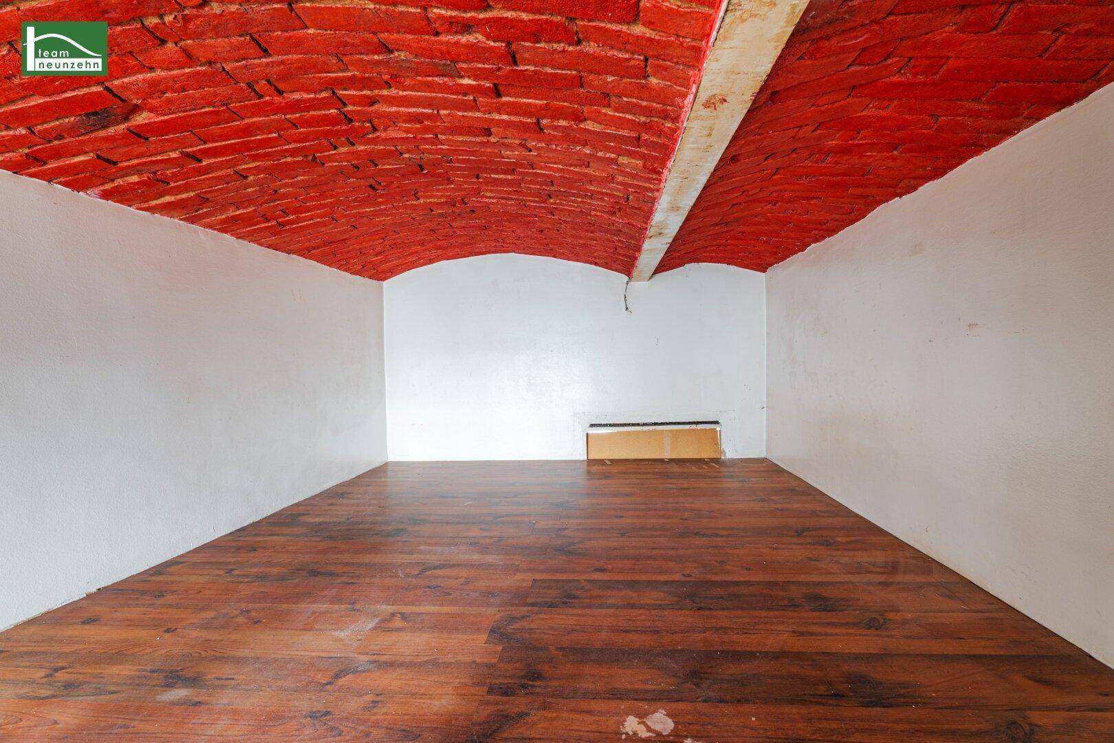 Geräumiger Raum mit markanter gewölbter Ziegeldecke und dunklem Holzboden.