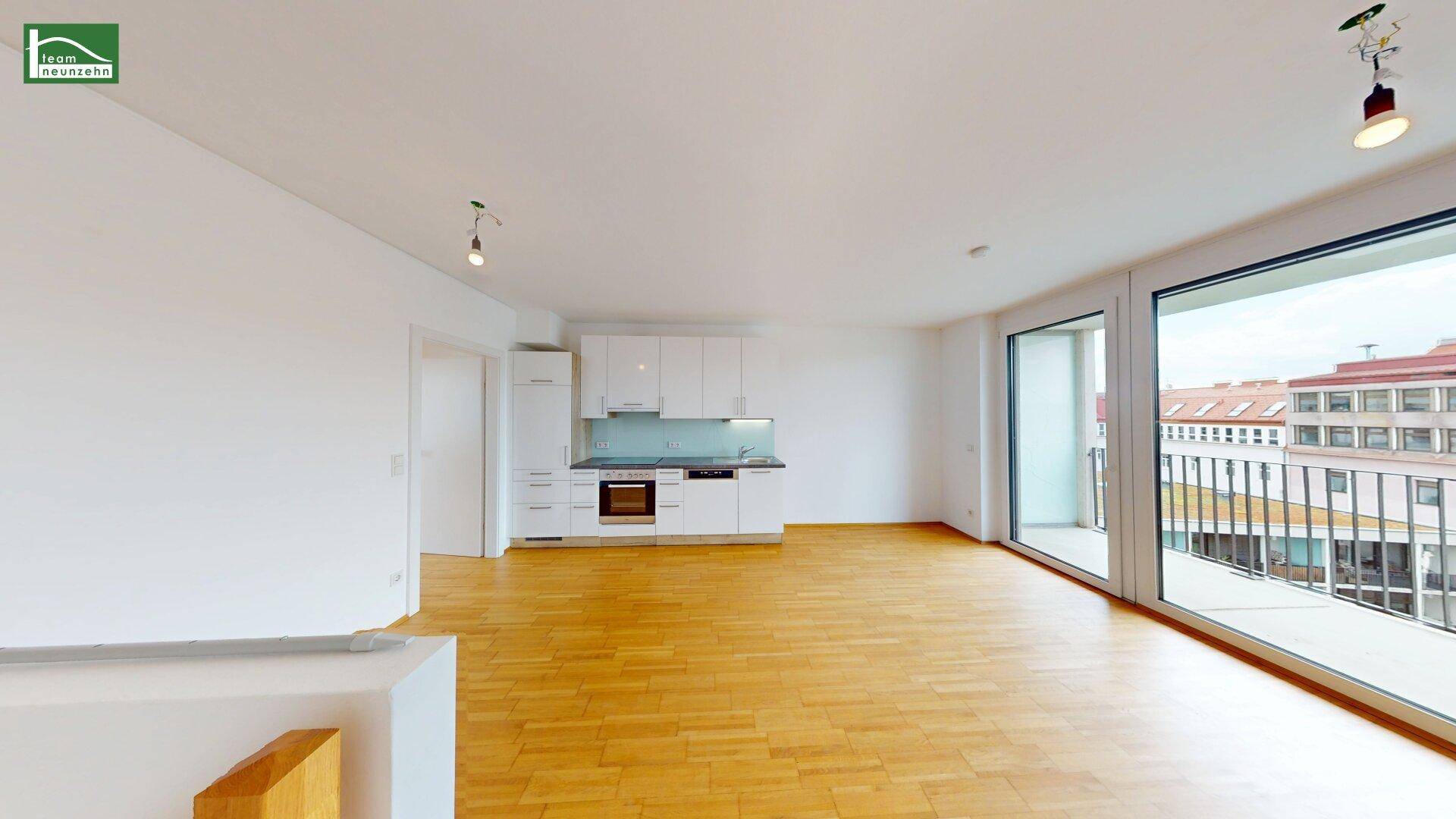 Heller Wohnbereich mit Zugang zum Balkon und integrierter Küchenzeile, ausgestattet mit Parkettboden.