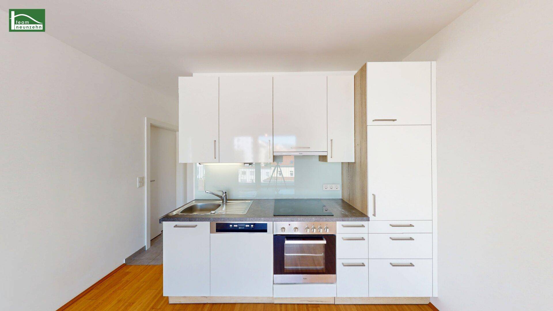 Moderne Einbauküche mit weißen Schränken, integriertem Backofen und Induktionskochfeld.
