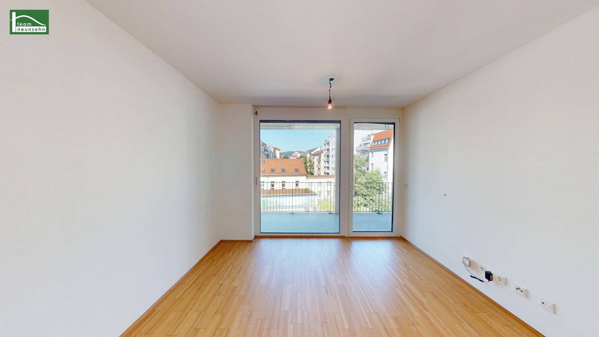 Helles, leeres Zimmer mit Holzboden und Zugang zu einem Balkon, ideal für individuelle Gestaltung.